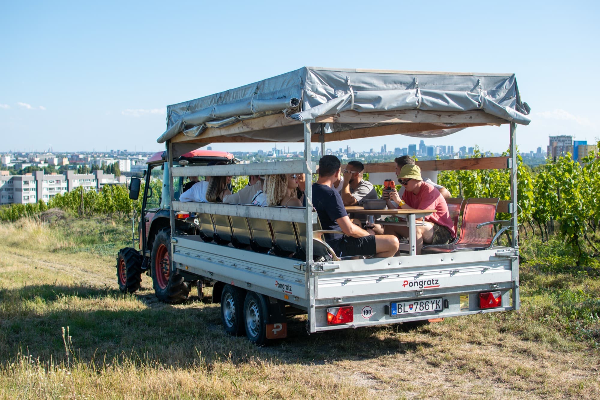Hostia na vlečke traktora vo vinohradoch nad Bratislavou